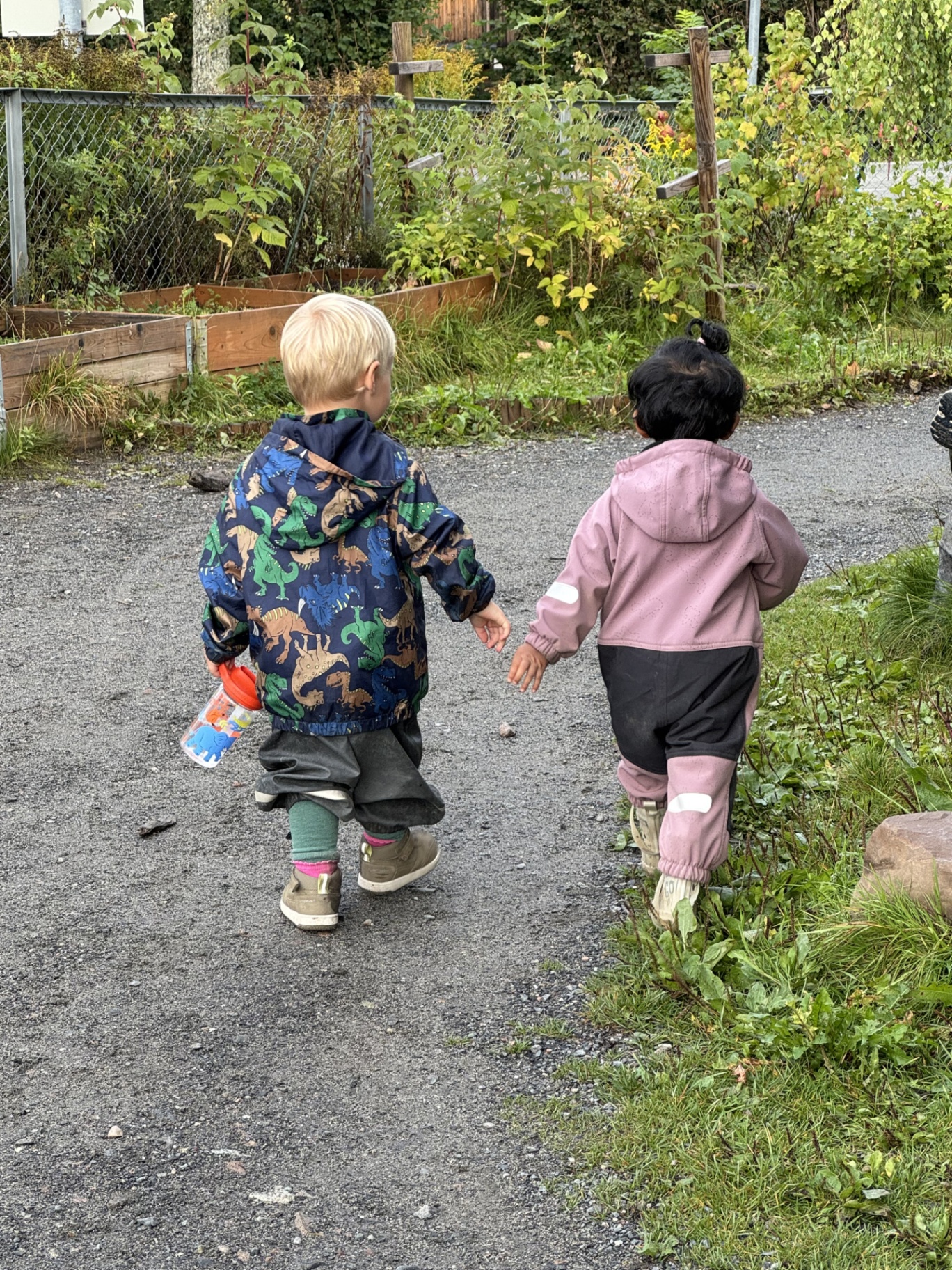 To barn går hånd i hånd på grusvei en høstdag
